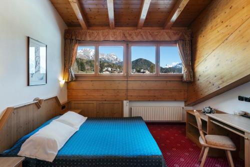 a bedroom with a bed and a desk and a window at Sport Hotel Cristal in Falcade