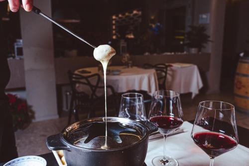 a person pouring wine into a pot on a table with wine glasses at Hotel Morgana in Mendrisio