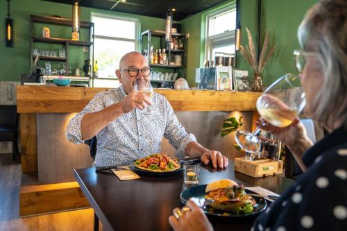 an older man and woman sitting at a table drinking wine at Camping Tussen de Diepen in Blokzijl