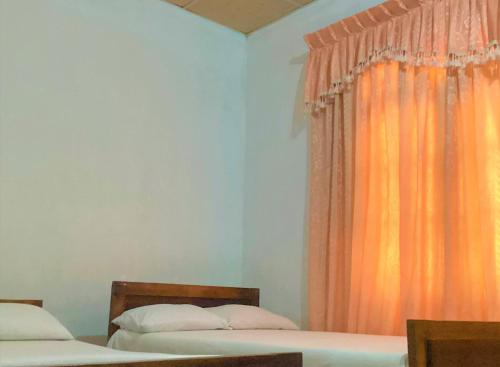 a bedroom with two beds and an orange curtain at Grand Refuge Holiday Rooms in Anuradhapura