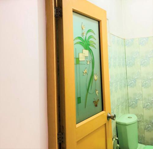 a bathroom door with a painting of a palm tree at Grand Refuge Holiday Rooms in Anuradhapura
