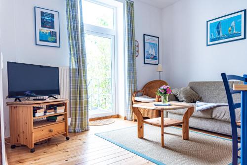 a living room with a couch and a tv at Haus Silko - FeWo in top Lage - 3 min zum Strand direkt am Kurpark in Warnemünde