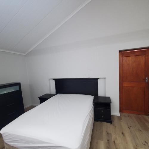 a bedroom with a white bed and a wooden cabinet at Kupenda Africa in Montagu