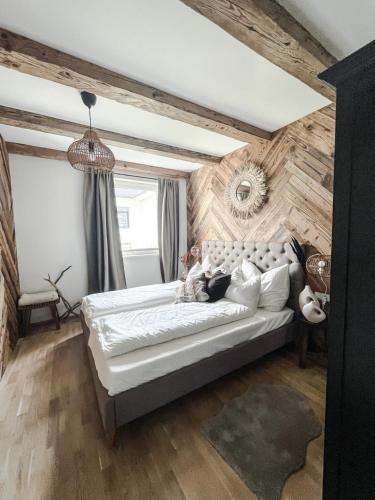 a bedroom with a large bed and a wooden wall at Bergzeit by Alpenidyll Apartments in Aich