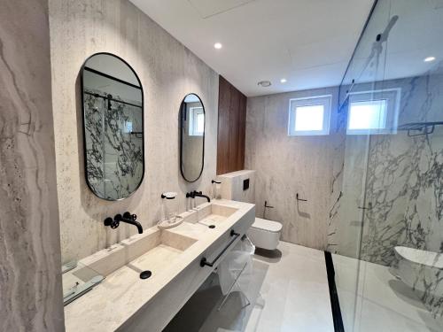 a bathroom with two sinks and a toilet and mirrors at Nad Al Sheba 3 - 5BR Villa - Allsopp&Allsopp in Dubai