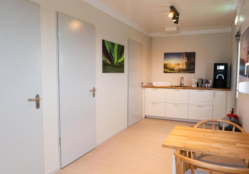 a kitchen with white cabinets and a wooden table at Aurora Igloo South in Hella