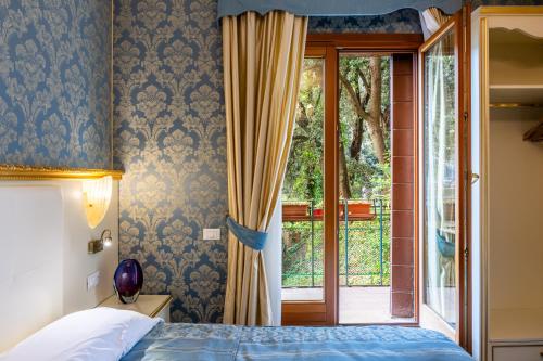 ヴェネツィアにあるホテル イル メルカンテ ディ ベネツィアのベッドルーム1室(ベッド1台付)、スライド式ガラスドアが備わります。