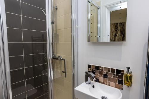 Un baño con lavabo, ducha y espejo. en Tan-Y-Ffordd - Tenby, en Tenby