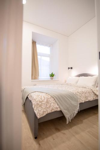 a white bedroom with a bed and a window at Lukiskes square apartment (Oldtown) in Vilnius