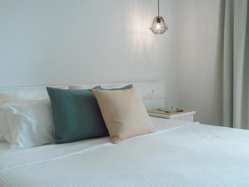 a bed with blue and white pillows and a lamp at Dracos Hotel in Parga