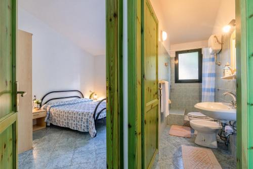 y baño con cama, lavabo y aseo. en Libeccio Sea view house, en Badesi