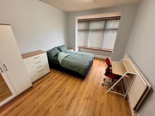 Schlafzimmer mit einem Bett, einem Schreibtisch und einem Fenster in der Unterkunft Langleys Private Double Room Selly Oak in Birmingham