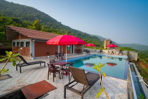 una piscina con sillas, mesas y sombrillas en Gaurav Lords Resort en Srīvardhan