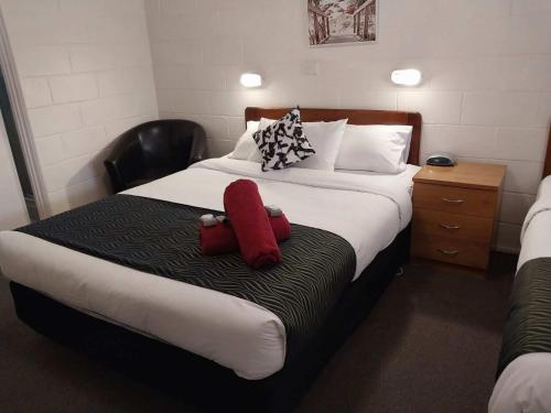 een hotelkamer met een bed met twee rode kussens bij Golden Peak Motel PeakHill in Peak Hill
