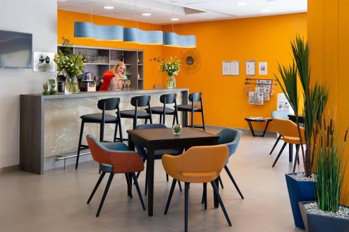 a restaurant with a bar with chairs and a woman in the kitchen at Domitys - L'Atlas in Arras