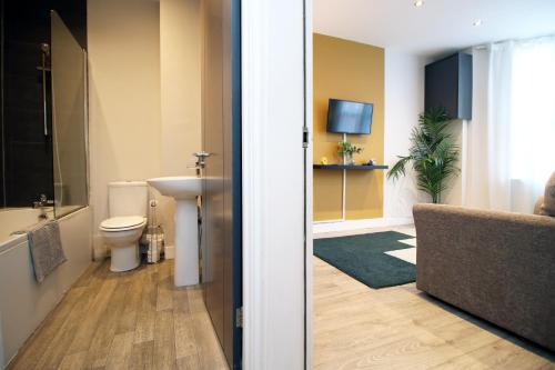 a bathroom with a toilet and a sink and a television at NEW 1 Bed Flat next to Roath Park w/Street Parking in Cardiff