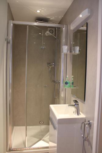 a shower with a glass door next to a sink at Level 15 Accommodation in Buxton