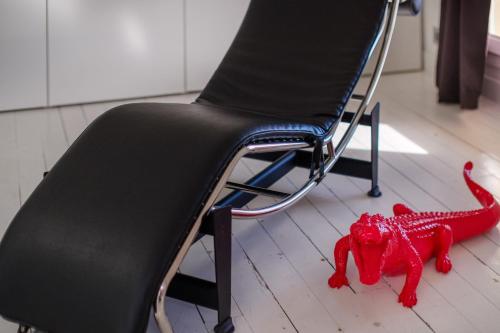 a red dinosaur toy on the floor next to a chair at Appartement de luxe - Bluesky in Beausoleil