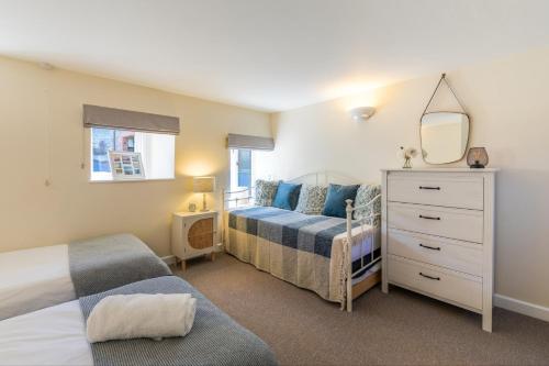 a bedroom with two beds and a mirror and a dresser at Putts Cottage in Braunton