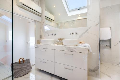 a white bathroom with two sinks and a mirror at Appartement de luxe - Bluesky in Beausoleil