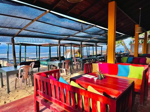 ヒッカドゥワにあるドリフターズ ホテル ＆ ビーチ レストランのビーチ沿いのカラフルなベンチとテーブルのあるレストラン