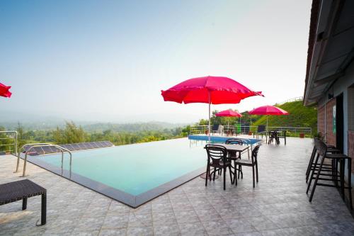 a swimming pool with tables and chairs and umbrellas at Gaurav Lords Resort in Srīvardhan