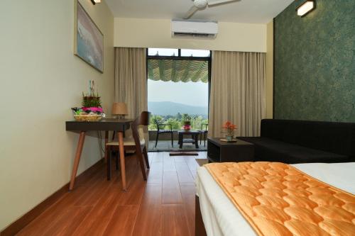 a hotel room with a bed and a table and a couch at Gaurav Lords Resort in Srīvardhan