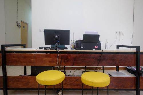 two yellow chairs sitting at a desk with a computer at Urbanview Hotel AVA Semarang near Akademi Kepolisian Semarang by RedDoorz in Jatingaleh
