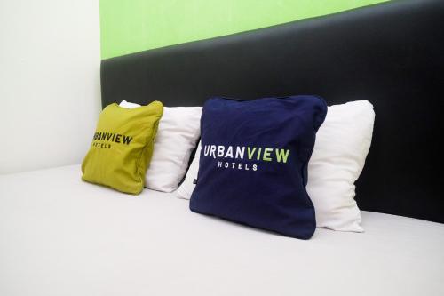 three pillows sitting on top of a bed at Urbanview Hotel AVA Semarang near Akademi Kepolisian Semarang by RedDoorz in Jatingaleh