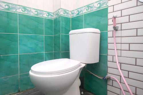 a bathroom with a white toilet with a pink hose at Urbanview Hotel AVA Semarang near Akademi Kepolisian Semarang by RedDoorz in Jatingaleh