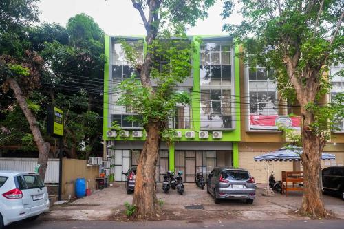 a green building with cars parked in front of it at Urbanview Hotel AVA Semarang near Akademi Kepolisian Semarang by RedDoorz in Jatingaleh