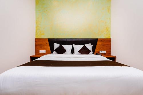 a bedroom with a large white bed with two pillows at Hotel Raheja Residency in Mumbai