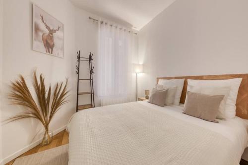 ein Schlafzimmer mit einem großen weißen Bett mit einer Pflanze in der Unterkunft Le Paisible Parisien à 3 minutes du métro in Vincennes