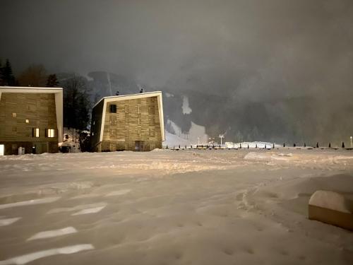 a snow covered field with a building in the background at Srna Apartment - Bjelašnica in Bjelašnica