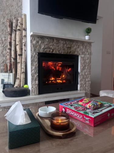 a living room with a fireplace and a table with a box at Srna Apartment - Bjelašnica in Bjelašnica