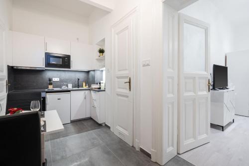 eine Küche mit weißen Schränken und einer weißen Tür in der Unterkunft Stellar Dwell Apartment in Budapest