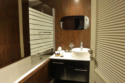 a bathroom with a sink and a mirror and a shower at PLAYA DEL PACHA Suites Hotel in Marina Smir