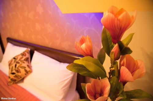 a vase with flowers in it next to a bed at Elena Rista Studios in Parga