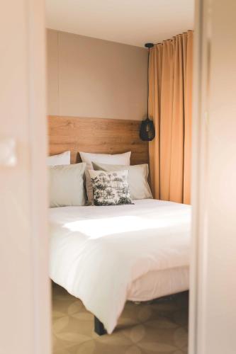 a bedroom with a white bed with a wooden headboard at Regenbogen Tossens in Butjadingen