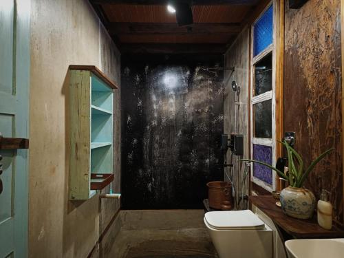 a bathroom with a toilet and a window at Svarna in Udupi