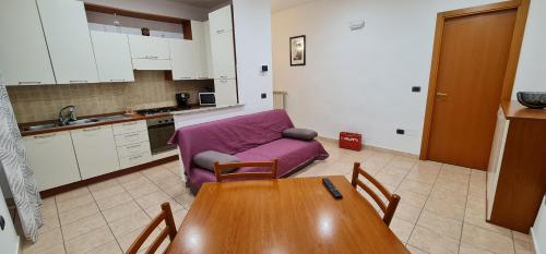 salon ze stołem i fioletową kanapą w obiekcie La Casetta di Flò - Alloggio per Turisti w mieście Marta