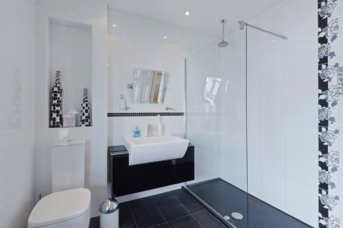 a white bathroom with a sink and a shower at Old Wharf Cottage - Riverside Living with Pool in Wraysbury