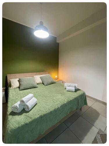 a bedroom with a green bed with towels on it at Domeanto home in Catania