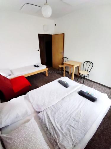 シュムペルクにあるPenzion Nikolのベッド2台、テーブル、椅子が備わる客室です。