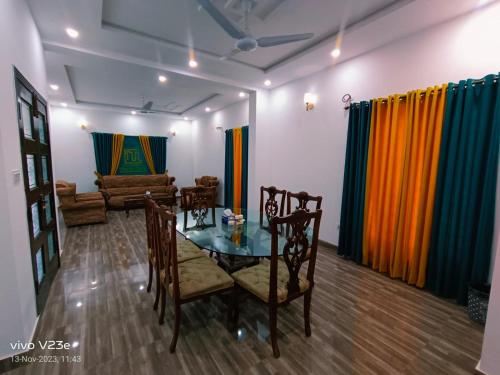 a dining room with a table and chairs and a couch at ITL GUESTHOUSE in Rawalpindi