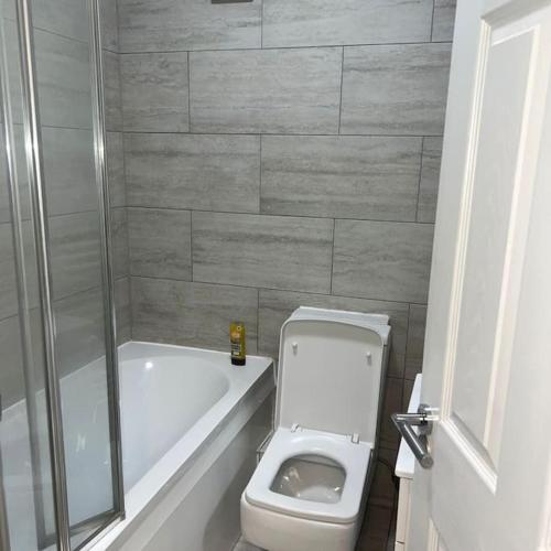 La salle de bains est pourvue de toilettes, d'une douche et d'une baignoire. dans l'établissement Beatle Luxy Apartment, à Feltham