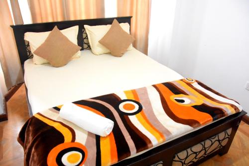 a bed with a black and orange blanket on it at The Dew Drop Villa in Nuwara Eliya