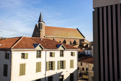 a large white building with a church in the background at Serra Boutique Hôtel in Agen