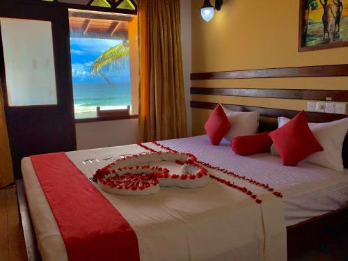 ヒッカドゥワにあるドリフターズ ホテル ＆ ビーチ レストランのベッドルーム1室(赤と白の枕が備わるベッド1台付)