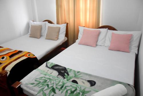 2 camas individuales en una habitación con almohadas rosas en The Dew Drop Villa, en Nuwara Eliya